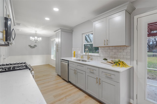 kitchen featuring decorative backsplash, stainless steel appliances, gray cabinetry, light wood-type flooring, and a sink