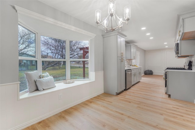 kitchen featuring light wood-style flooring, gray cabinets, stainless steel appliances, light countertops, and backsplash