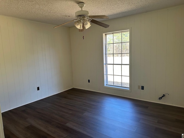 unfurnished room with a textured ceiling, dark wood finished floors, and a healthy amount of sunlight