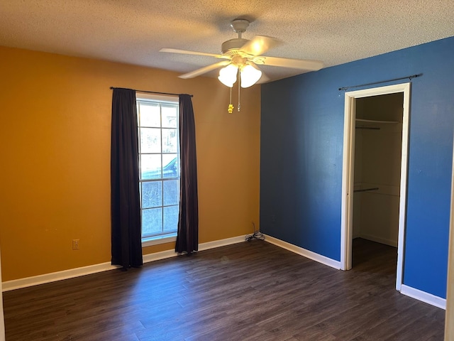 empty room featuring dark wood-style floors, a textured ceiling, and baseboards