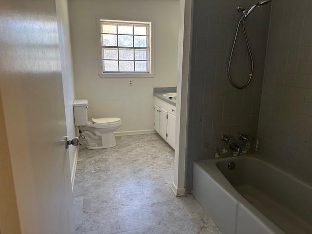 bathroom featuring washtub / shower combination, vanity, toilet, and baseboards