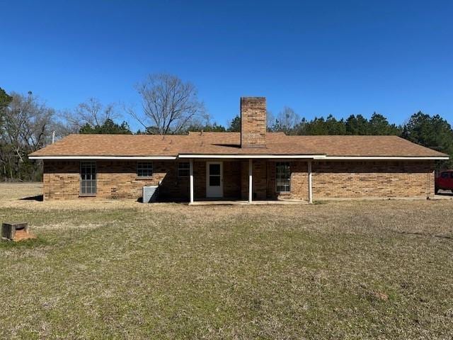 rear view of house featuring brick siding and a chimney