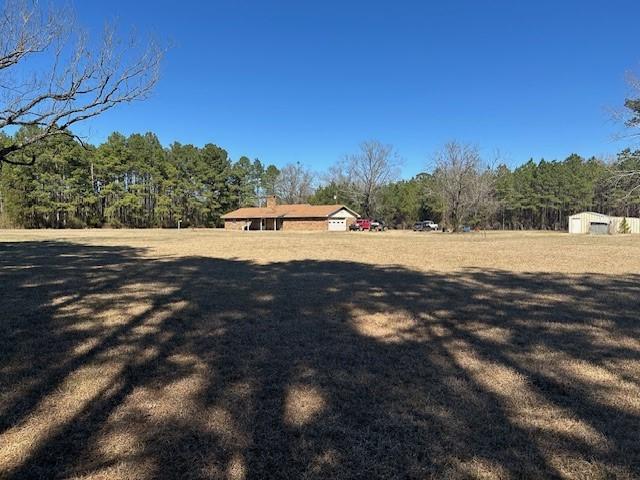 view of yard with a storage shed, an outdoor structure, and a wooded view