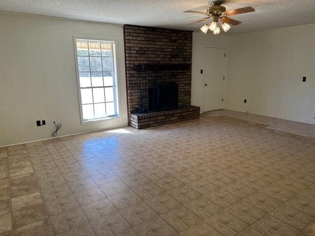 unfurnished living room featuring ceiling fan, a fireplace, a textured ceiling, and tile patterned floors