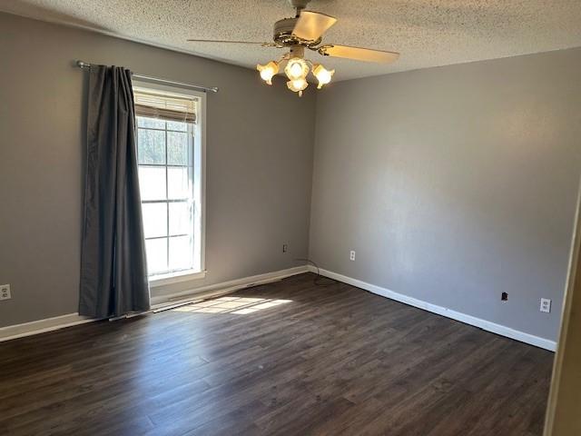 spare room featuring dark wood-style floors, a textured ceiling, and baseboards