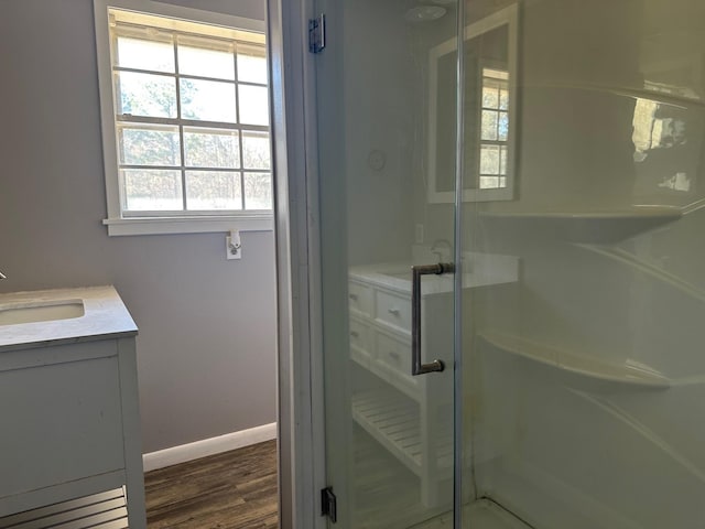 bathroom featuring baseboards, a shower stall, vanity, and wood finished floors