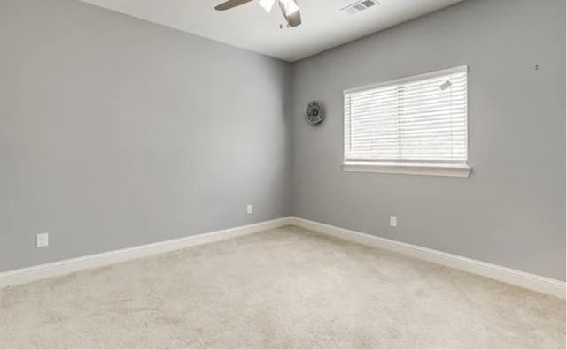 empty room with light colored carpet, visible vents, ceiling fan, and baseboards