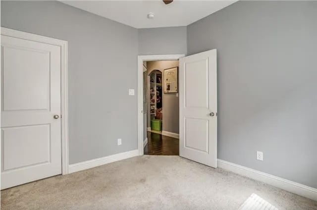 unfurnished bedroom with carpet, baseboards, and a ceiling fan