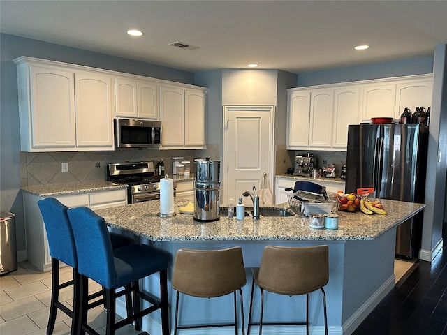 kitchen featuring light stone countertops, white cabinetry, visible vents, and appliances with stainless steel finishes