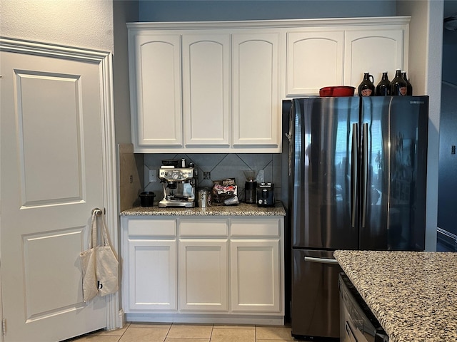 kitchen with stone counters, freestanding refrigerator, and white cabinets