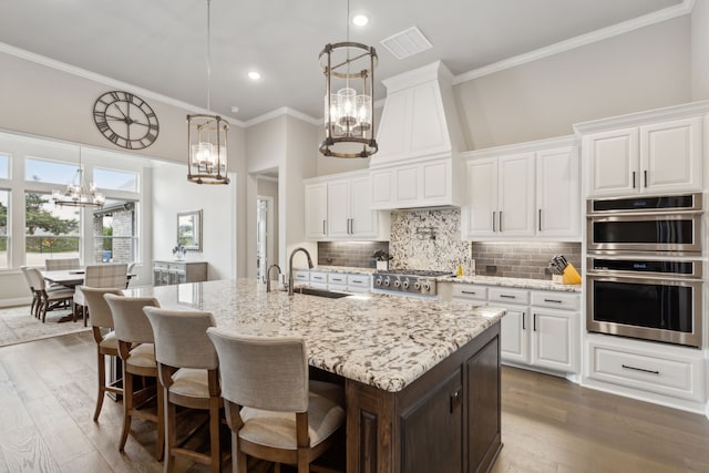 kitchen with a chandelier, a sink, visible vents, appliances with stainless steel finishes, and custom range hood