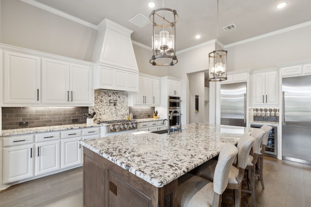 kitchen featuring a sink, white cabinetry, ornamental molding, appliances with stainless steel finishes, and light wood-type flooring