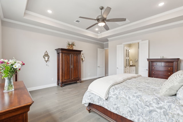 bedroom with ornamental molding, light wood-type flooring, and a raised ceiling