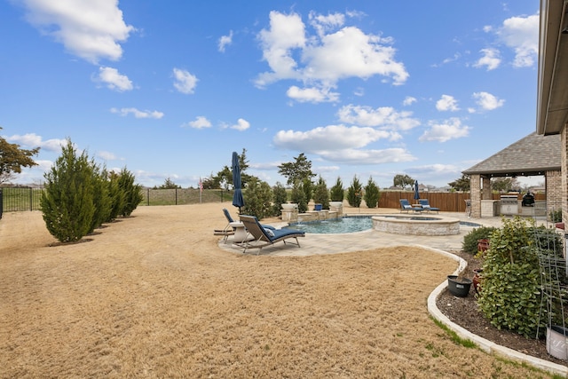 view of yard with exterior kitchen, a pool with connected hot tub, a fenced backyard, and a patio