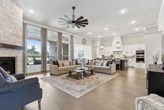 living area with a fireplace, recessed lighting, light wood-style flooring, ornamental molding, and ceiling fan