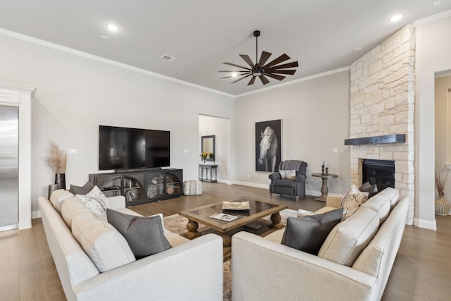 living area with a fireplace, visible vents, ornamental molding, ceiling fan, and wood finished floors