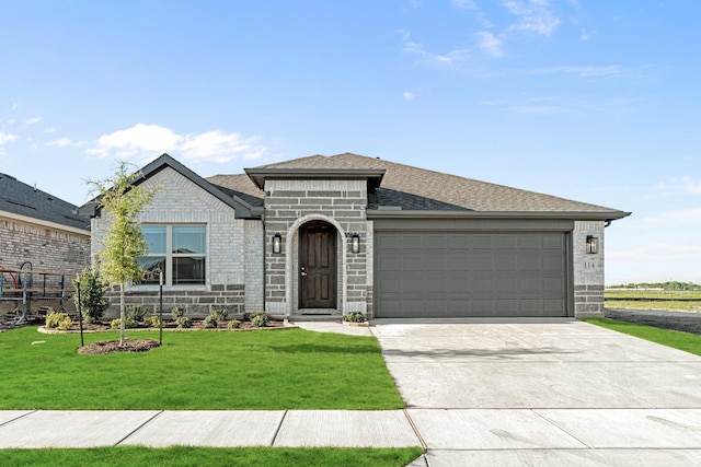 view of front of property featuring a front yard, a garage, brick siding, driveway, and roof with shingles