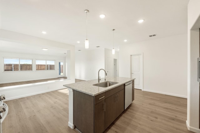 kitchen with pendant lighting, dark brown cabinetry, dishwasher, a sink, and light wood finished floors