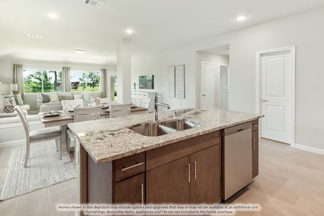 kitchen with light stone counters, a kitchen island with sink, a sink, and dishwasher