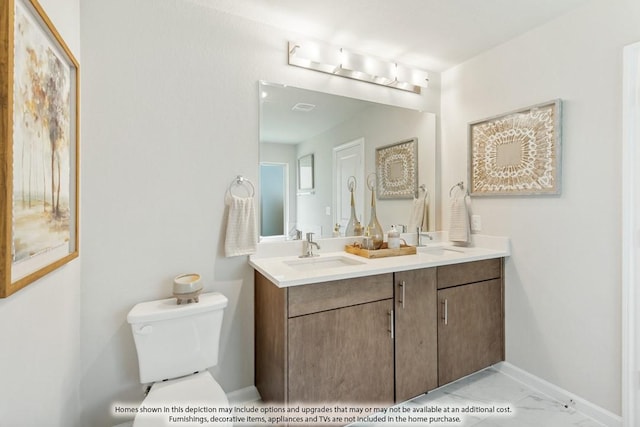 full bath with marble finish floor, double vanity, toilet, a sink, and baseboards