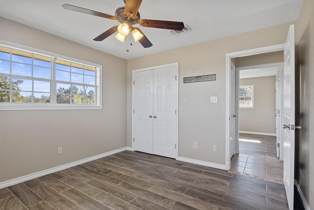 unfurnished bedroom with wood tiled floor, visible vents, baseboards, and multiple windows