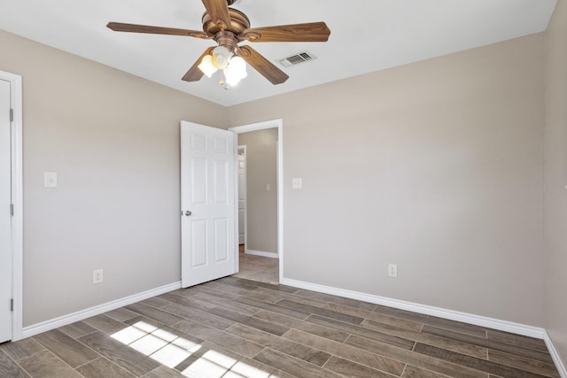 spare room featuring baseboards, a ceiling fan, visible vents, and wood tiled floor