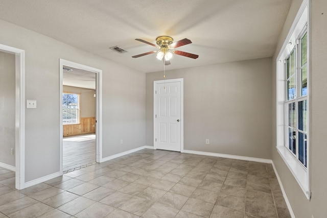 spare room featuring visible vents, ceiling fan, a textured ceiling, and baseboards