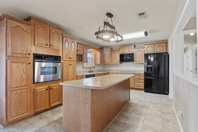 kitchen featuring visible vents, a kitchen island, decorative light fixtures, light countertops, and black appliances