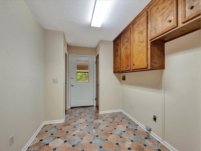 laundry area featuring baseboards, a textured ceiling, cabinet space, and electric dryer hookup