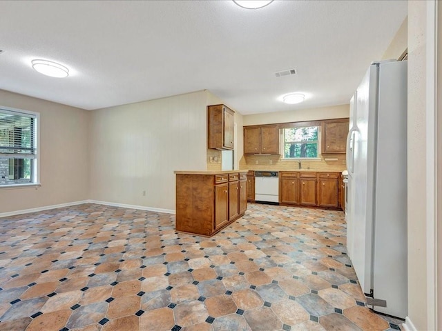 kitchen featuring white appliances, visible vents, light countertops, brown cabinets, and decorative backsplash