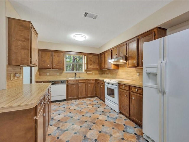 kitchen featuring tasteful backsplash, visible vents, a sink, white appliances, and under cabinet range hood