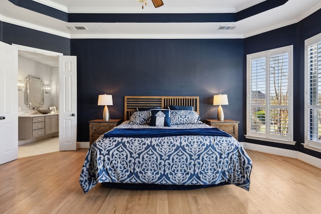 bedroom with a tray ceiling, crown molding, ceiling fan, light wood-type flooring, and baseboards