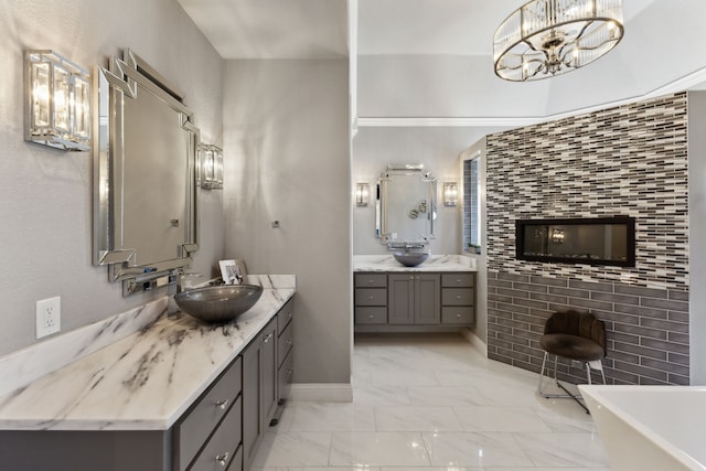 bathroom featuring two vanities, a sink, marble finish floor, a freestanding tub, and a notable chandelier