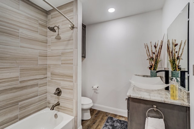 bathroom featuring shower / washtub combination, toilet, vanity, wood finished floors, and baseboards