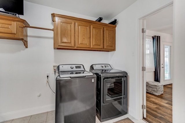 laundry room with light wood-style flooring, cabinet space, washer and clothes dryer, and baseboards