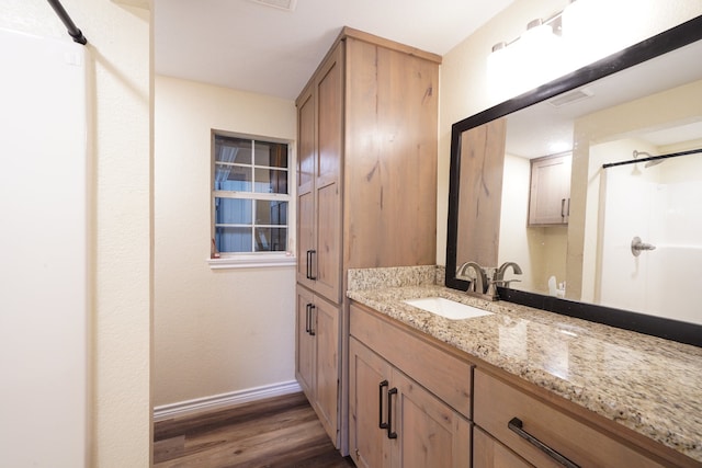 full bath with visible vents, vanity, wood finished floors, baseboards, and walk in shower