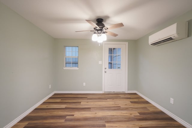 interior space with a ceiling fan, an AC wall unit, baseboards, and wood finished floors