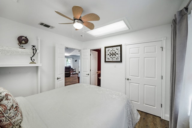 bedroom featuring a ceiling fan, attic access, visible vents, and dark wood-type flooring