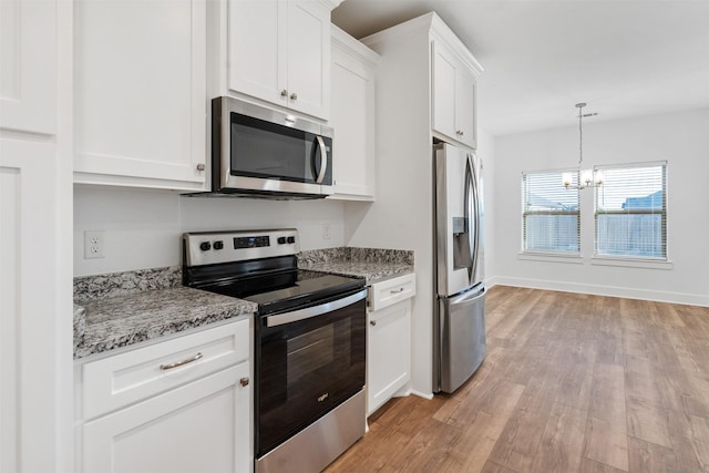 kitchen with light stone counters, white cabinets, appliances with stainless steel finishes, light wood-type flooring, and an inviting chandelier