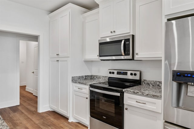 kitchen featuring light wood finished floors, baseboards, white cabinets, appliances with stainless steel finishes, and light stone countertops