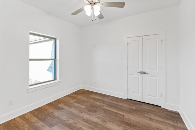 unfurnished room with ceiling fan, wood finished floors, and baseboards