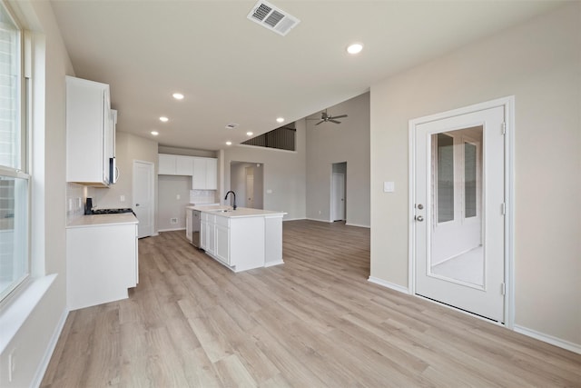 kitchen featuring dishwasher, open floor plan, a sink, and white cabinets