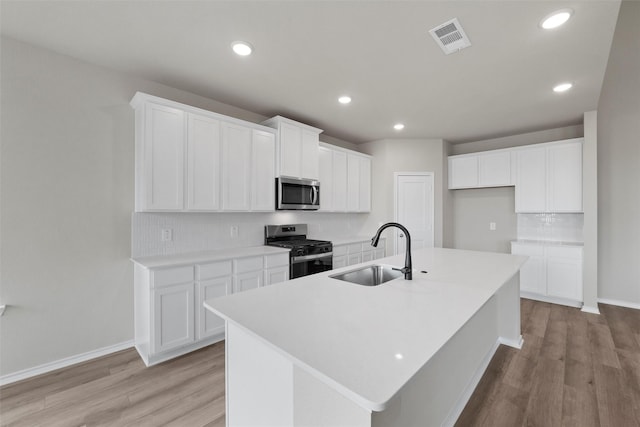 kitchen featuring a sink, visible vents, appliances with stainless steel finishes, decorative backsplash, and light wood finished floors