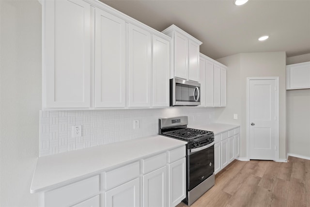 kitchen with appliances with stainless steel finishes, white cabinetry, light wood-style floors, and tasteful backsplash