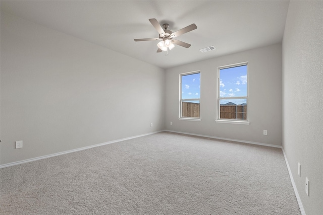 spare room with carpet floors, baseboards, visible vents, and a ceiling fan