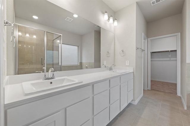 bathroom featuring a walk in closet, a sink, visible vents, and a shower stall