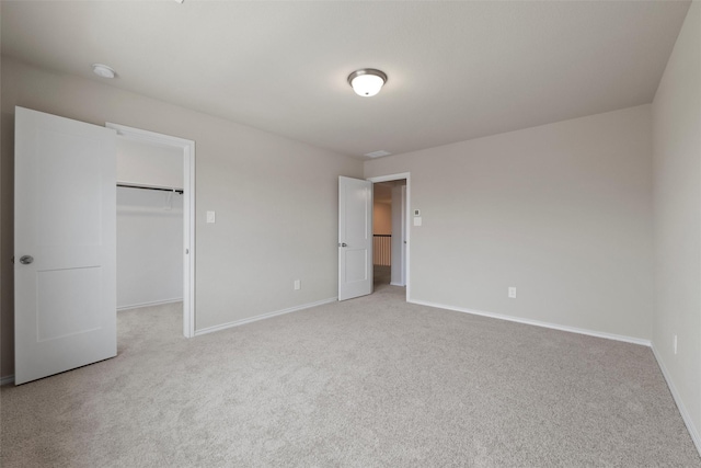 unfurnished bedroom with a closet, baseboards, a walk in closet, and carpet flooring