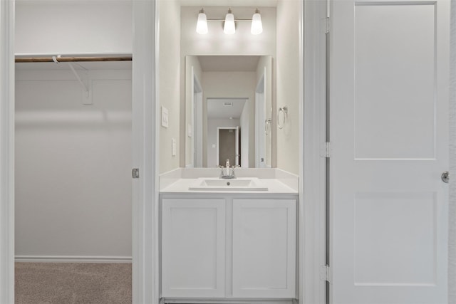 bathroom featuring baseboards, a walk in closet, and vanity