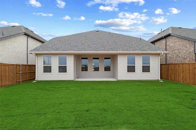 rear view of house with a shingled roof, a fenced backyard, a lawn, and a patio