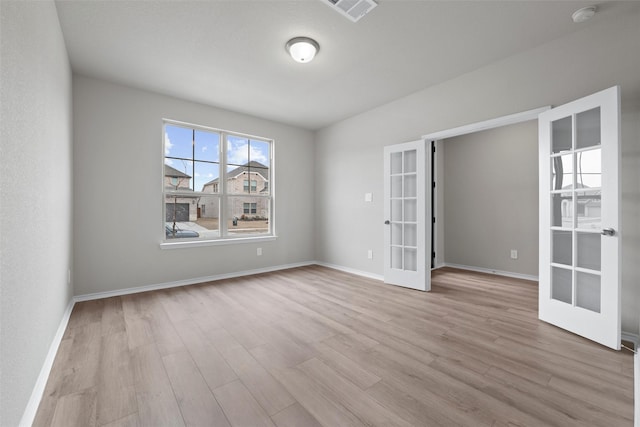 empty room with french doors, visible vents, baseboards, and wood finished floors